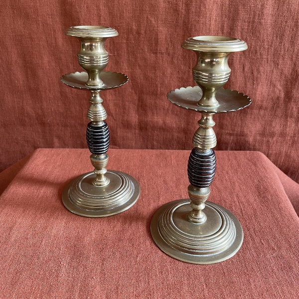 A pair of brass candlesticks with ebony wooden detail